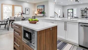 A modern kitchen with a central island, built-in oven, and stainless steel appliances.