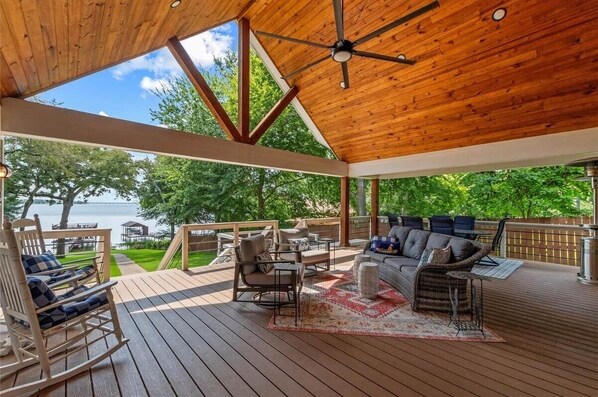 A covered deck with a wooden ceiling, outdoor furniture, and a view of a lake. - Holly Court Hideaway Lake House on a Spacious Private Wooded Lot (Eustace)