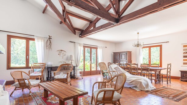 A spacious living room with wooden beams, a dining area, and a kitchen. - Family Home on the Edge of the Forest with Terrace, Private Garden, and Balcony (Le Grand-Village-Plage)