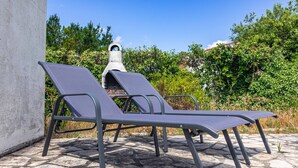 Two lounge chairs on a stone patio with a stone oven in the background. - Family Home on the Edge of the Forest with Terrace, Private Garden, and Balcony (Le Grand-Village-Plage)