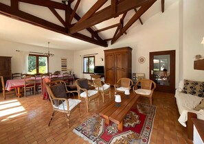 A spacious living room with wooden flooring, a dining area with a table and chairs, and a large wardrobe. - Family Home on the Edge of the Forest with Terrace, Private Garden, and Balcony (Le Grand-Village-Plage)