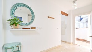 A hallway with a mirror, a potted plant, a small table, and a door leading to a balcony. - Oasis Tropical Apartment with Parking, Pool, and Air Conditioning (Almuñécar)