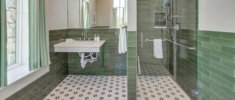 A bathroom with a sink, mirror, and shower area.