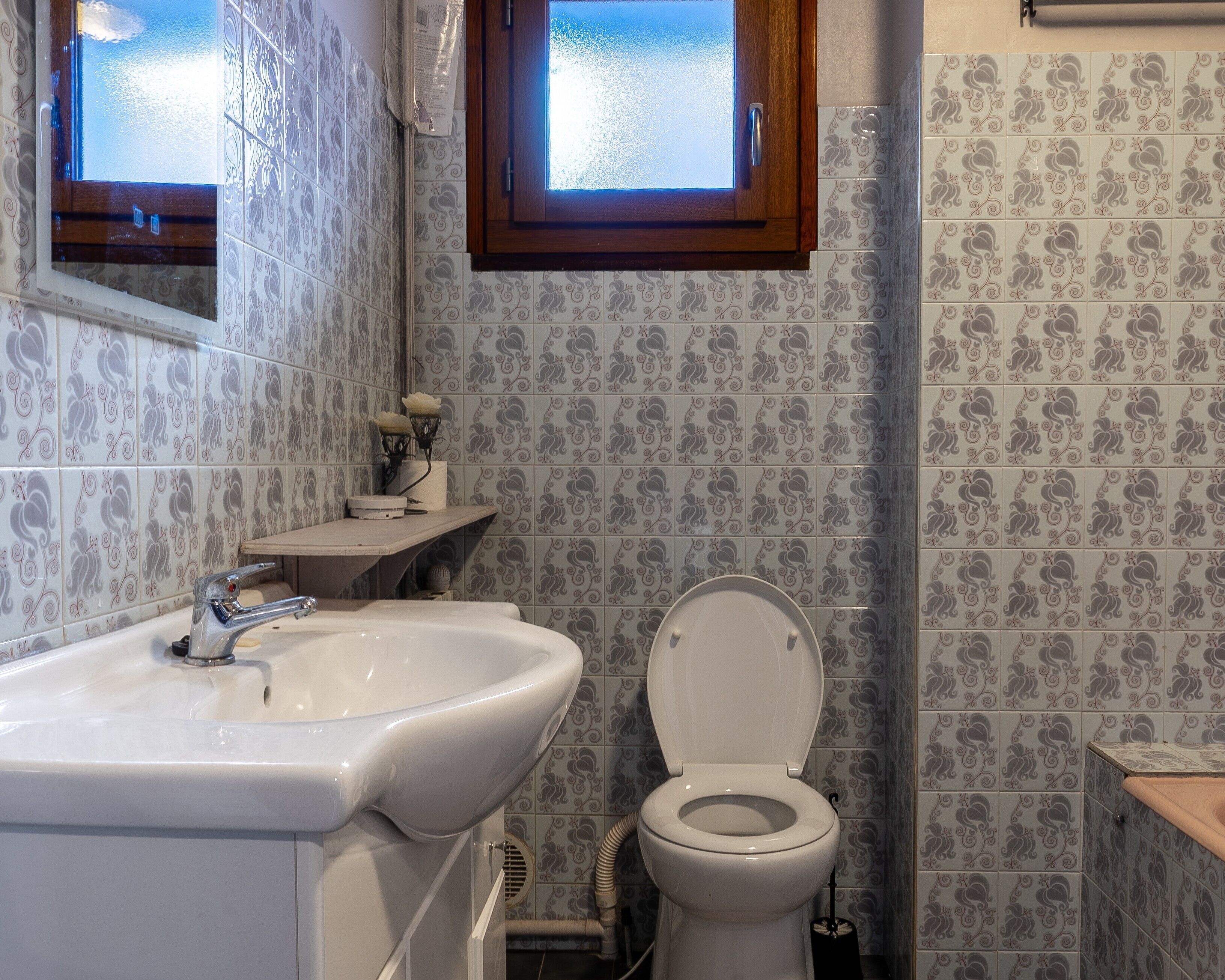 Un bagno con lavandino, WC e piastrelle decorate.