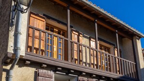 A building with a balcony, wooden shutters, and a window with a grid pattern.