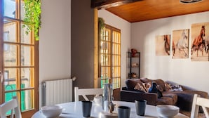 A dining area with a round table, chairs, and bowls. There is a window with a view of buildings outside.