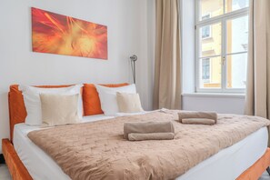 Habitació d'hotel amb un llit gran, una làmpada de peu, una finestra amb cortines i un quadre a la paret.