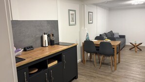 Une cuisine moderne avec un plan de travail en bois, des meubles noirs et un coin repas comprenant une table et des chaises.
