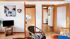 Ett vardagsrum med en tv, en fåtölj, en soffa, en hjärtformad dekoration och en tavla på väggen.