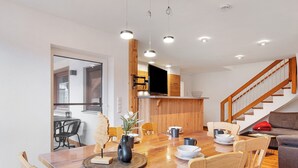 A modern dining area with a wooden table, chairs, and pendant lighting.