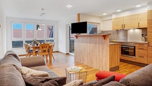 A modern kitchen with wooden cabinets, a built-in oven, and a dining area with a table and chairs.