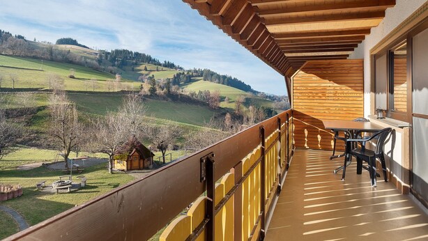 A balcony with a view of rolling hills, wooden railings, and a table with chairs. - Apartment Wiesenblick with Balcony and Wi-Fi (Horben)