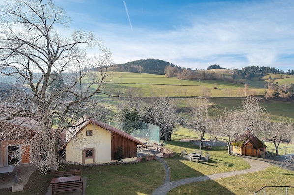 Ländliche Landschaft mit einem kleinen Holzhaus, einem gepflasterten Weg und einer Rasenfläche.