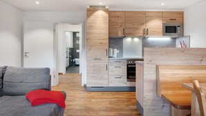 A modern kitchen with wooden cabinets, a microwave, and a dining area with a table and chairs. - Apartment Talblick with Balcony and Wi-Fi (Horben)