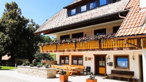 A traditional building with a balcony, outdoor seating, and a stone wall. - Double Room Apartment with Balcony and Wi-Fi (Horben)