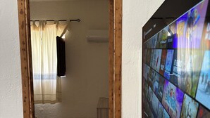 Un pasillo que conduce a una habitación con un televisor mostrando diferentes canales.