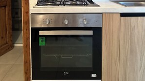 Una cocina con estufa a gas, horno y armarios de madera.