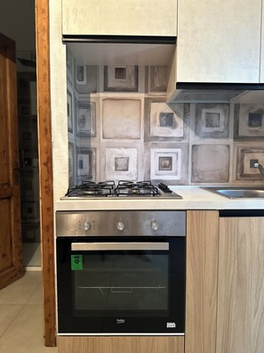 Une cuisine équipée d’une cuisinière à gaz, d’un four et de meubles de rangement en bois.