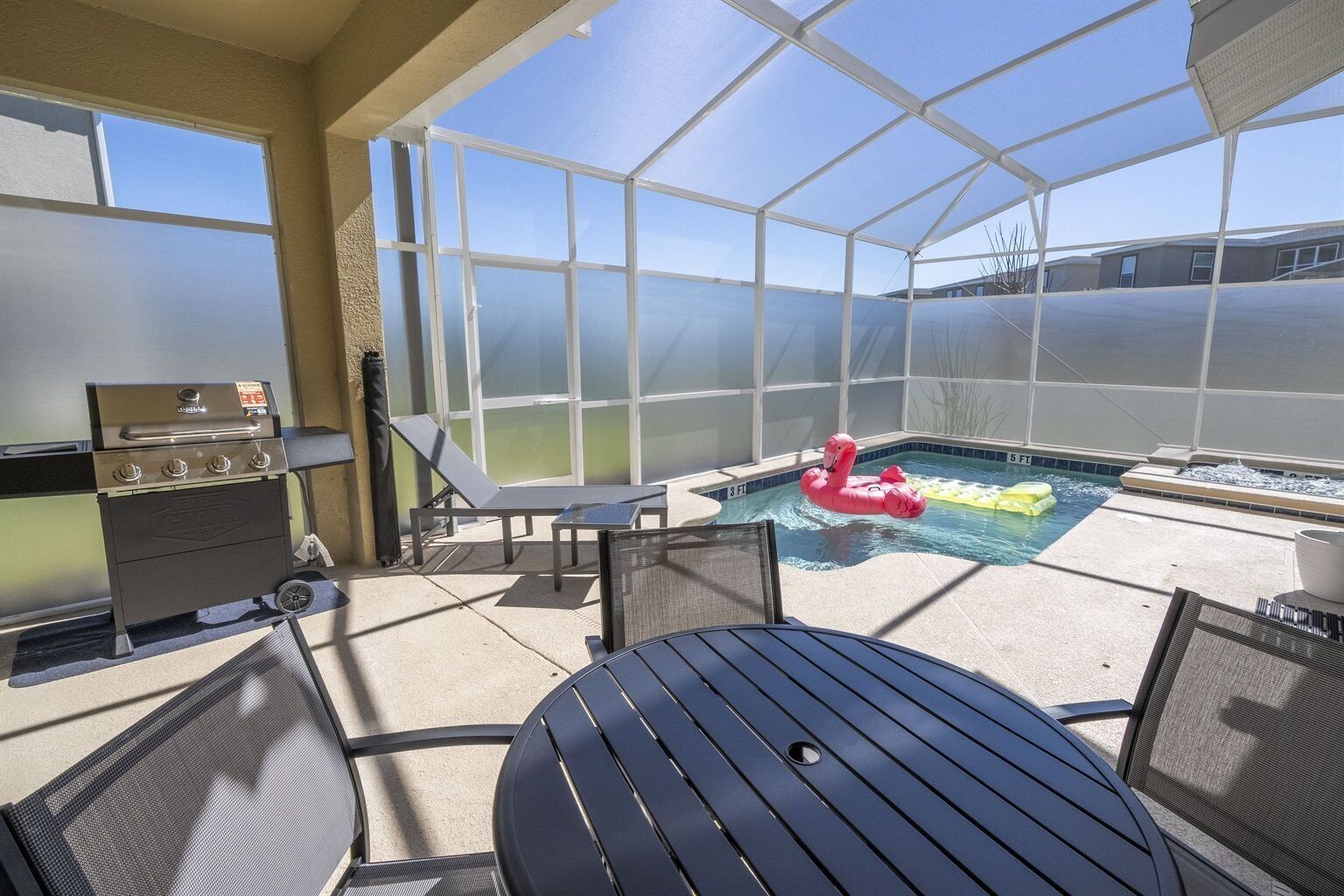 Un espace extérieur abrité comprenant une piscine, des chaises longues et un barbecue.