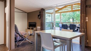 A room with a dining table, chairs, a TV, and a sofa.