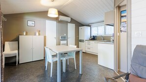 A compact kitchen with a dining table and chairs, a small refrigerator, and a window.