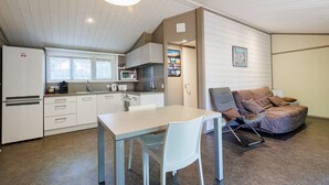 A compact kitchen with modern appliances, a dining area with a table and chairs, and a cozy seating area with a cushioned chair.