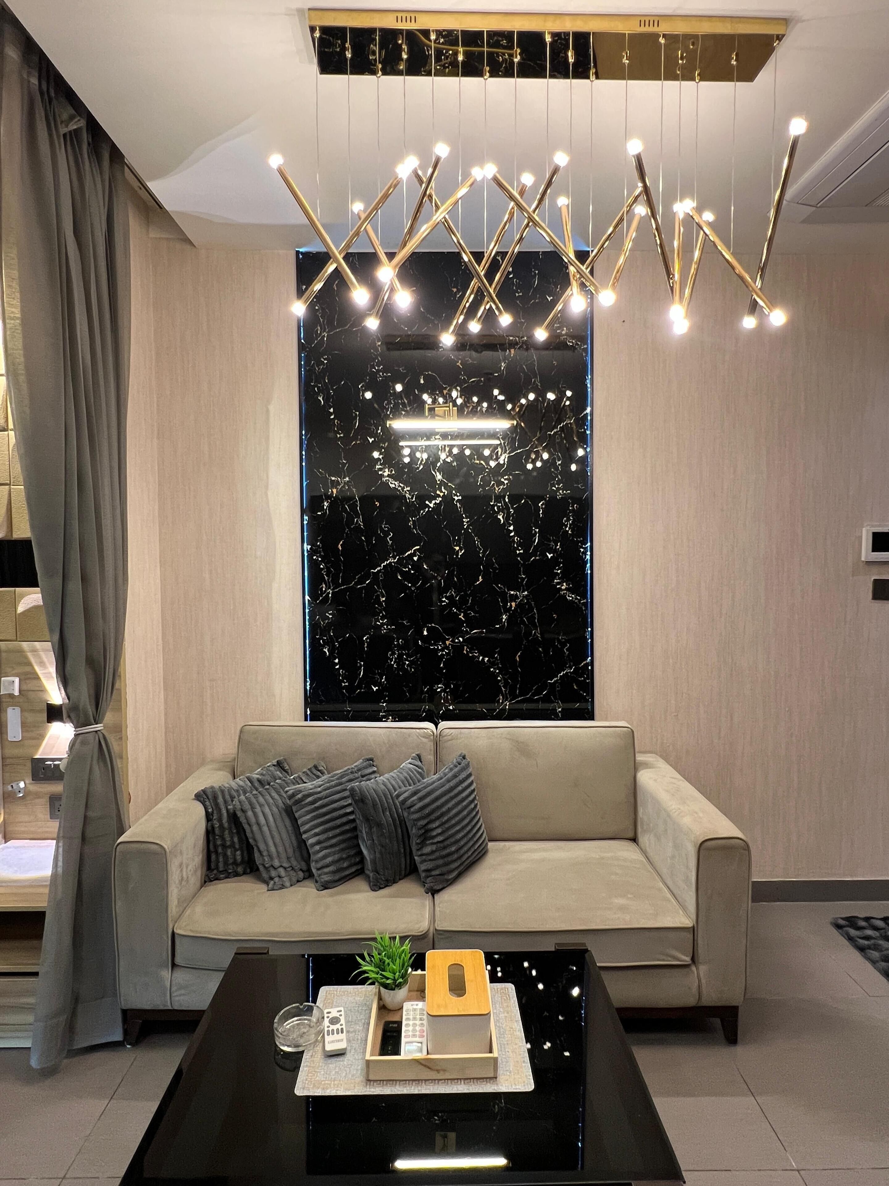 A modern living room with a sofa, a coffee table, and a unique ceiling light fixture.