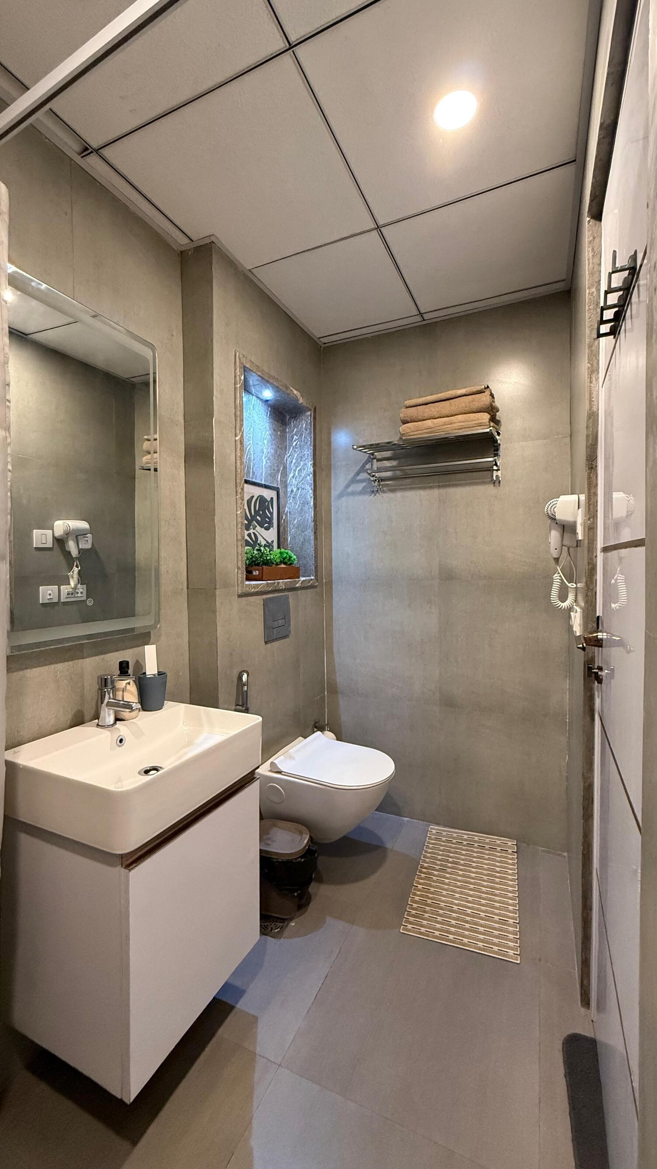 Un baño moderno con un espejo grande, un lavabo, un inodoro y una zona de ducha.