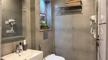 Un baño moderno con un espejo grande, un lavabo, un inodoro y una zona de ducha.