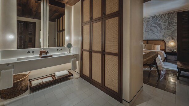 A modern bathroom with a large mirror, wooden paneling, a bathtub, and a wicker basket. - Del Alma Merida (Mérida)