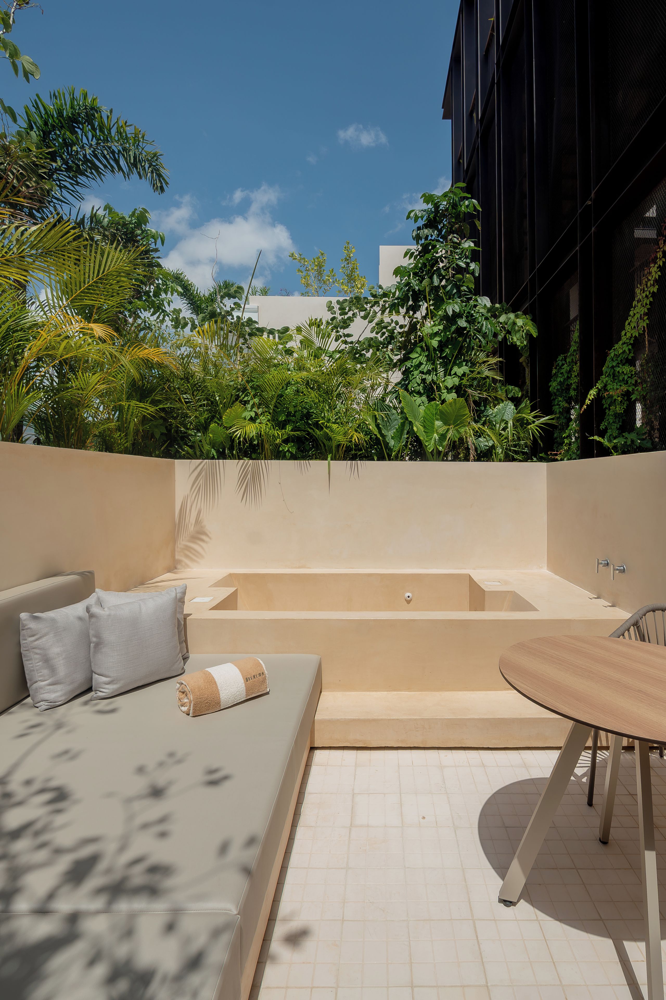 A modern outdoor seating area with a sofa, a table, and a bathtub.