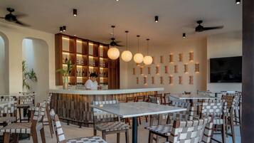 A restaurant interior with a bar area, seating arrangements, and a bartender.