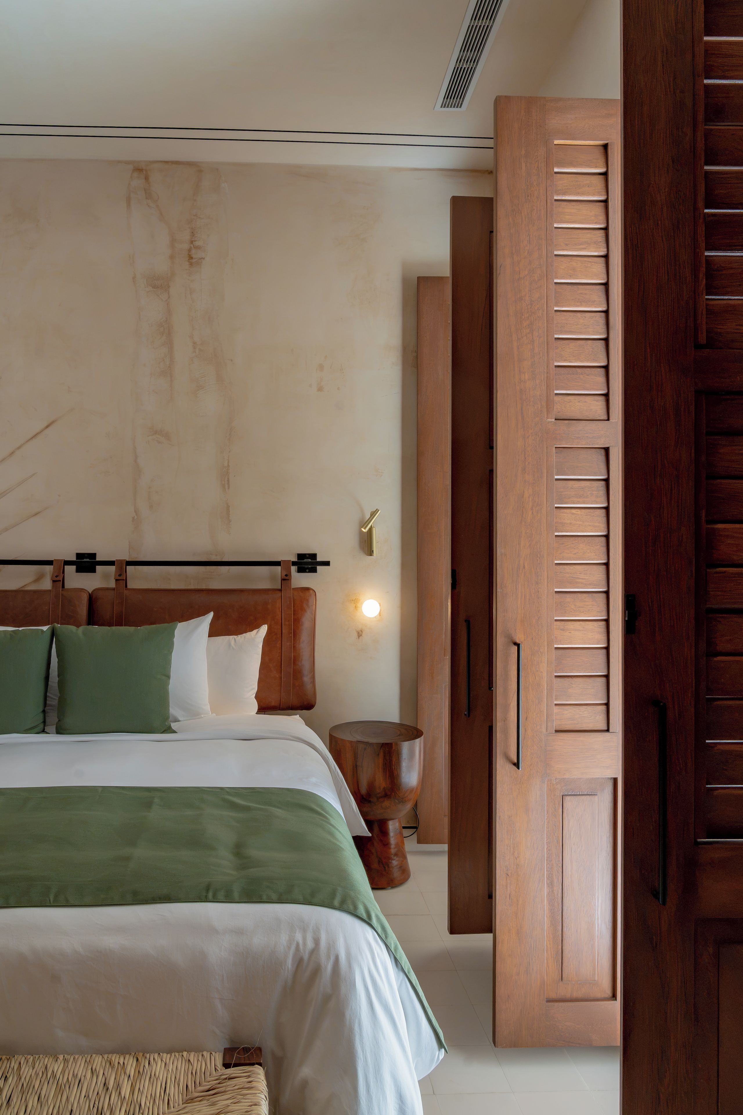 Une chambre à coucher avec un lit, une armoire en bois et un luminaire fixé au mur.