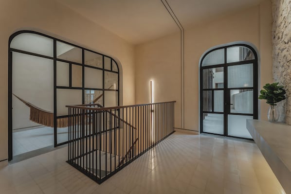A modern interior with a staircase, glass partitions, and a plant. - Del Alma Merida (Mérida)