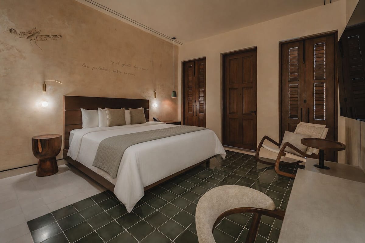 A bedroom with a bed, bedside tables, a chair, and a desk.