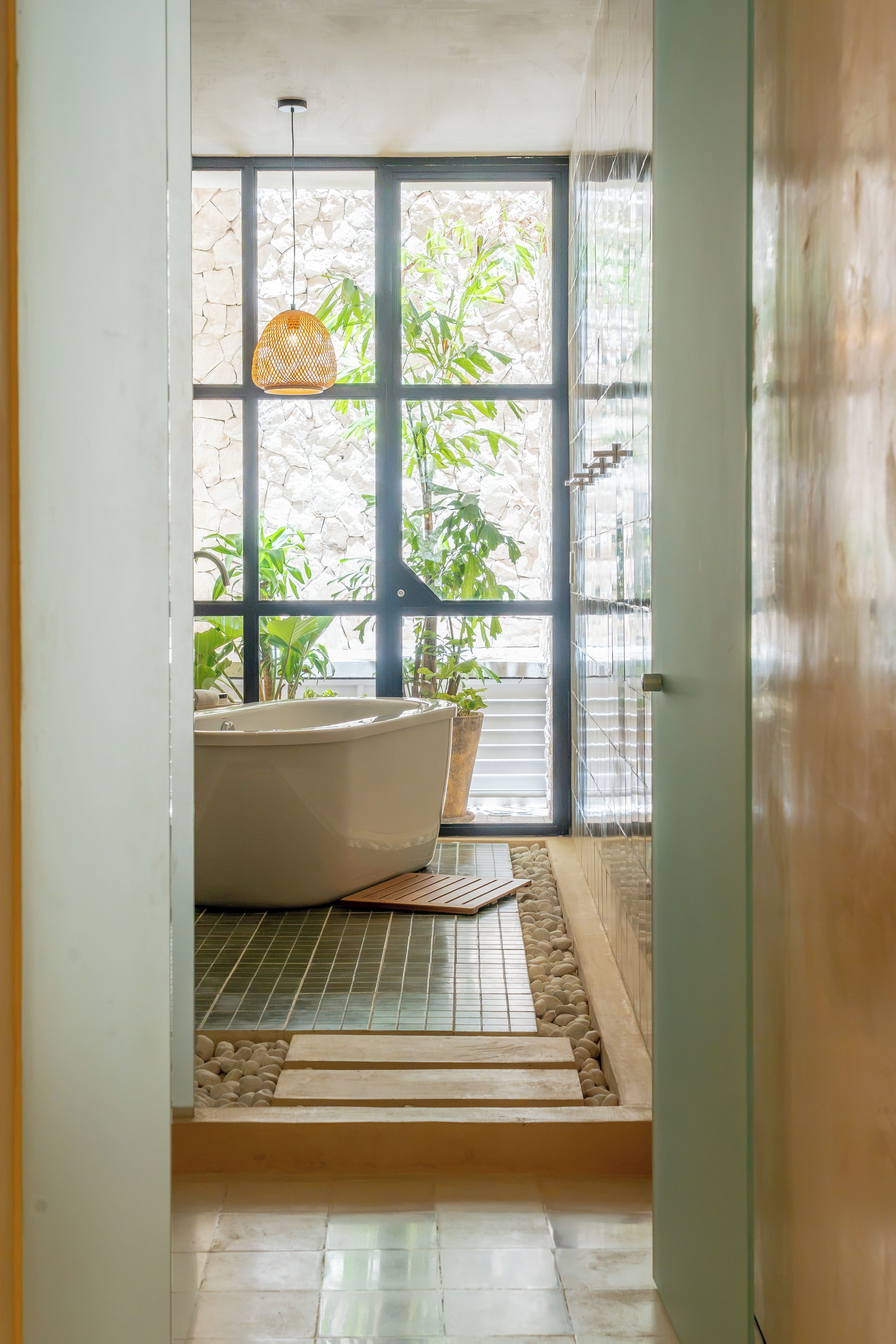 A bathroom with a bathtub, a potted plant, and a hanging light fixture.