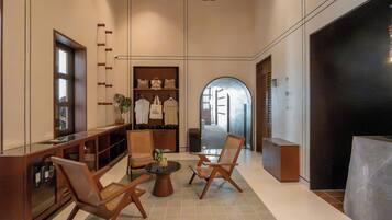 A spacious lobby with a seating area, a display of bags, and a view into another room.