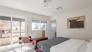 Ein Schlafzimmer mit einem Bett, einem Schreibtisch, einem Stuhl und einem großen Fenster.