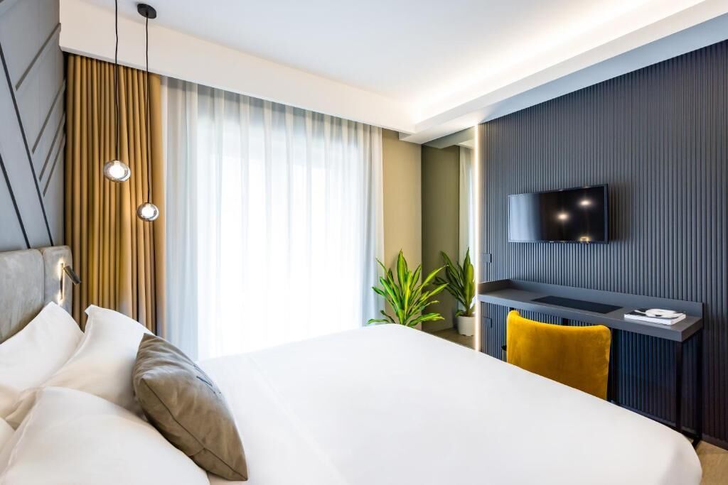 Een hotelkamer met een groot bed, een bureau met een flatscreen televisie en een raam met gordijnen.