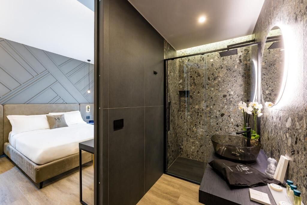 Une chambre d’hôtel moderne équipée d’un lit, d’une salle de bain avec un grand miroir et d’un espace douche.