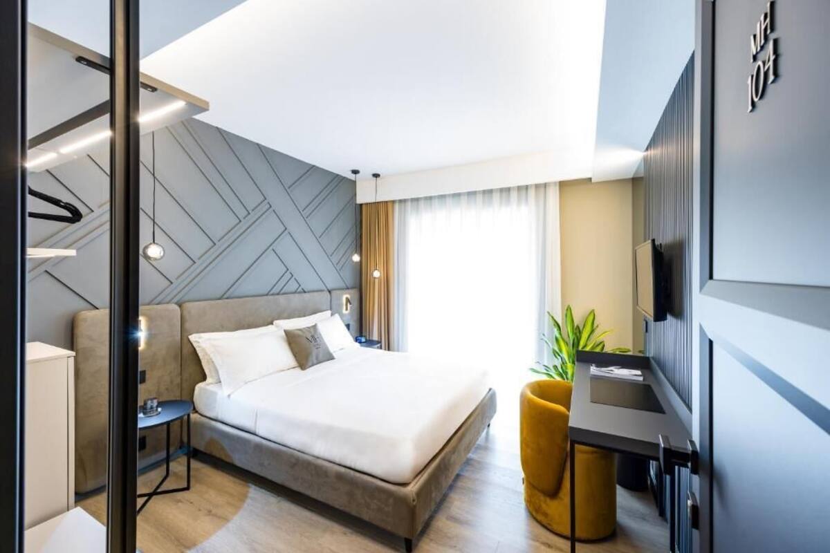 A modern hotel room with a large bed, bedside tables, a desk, and a TV.
