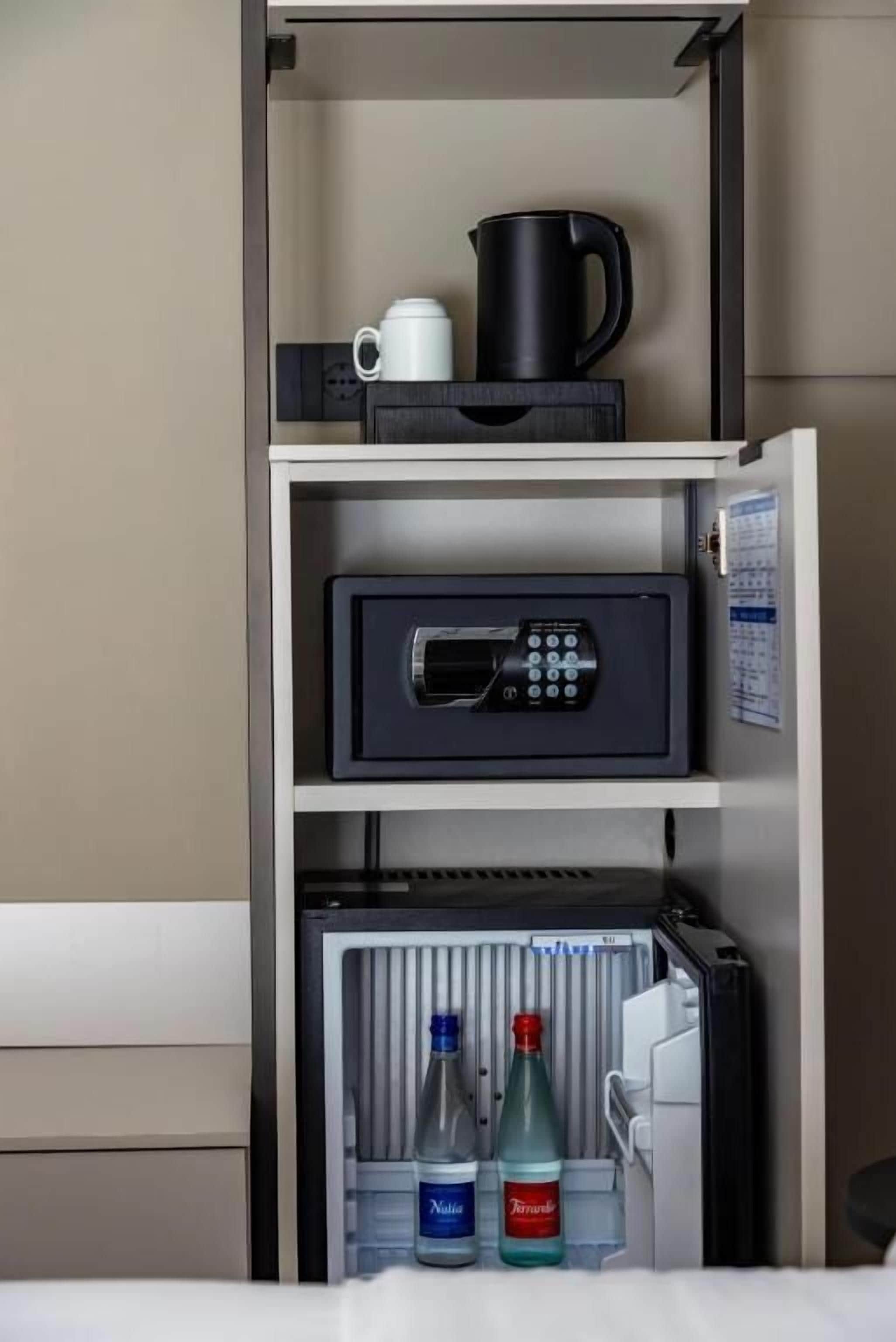 Un mini-bar comprenant une machine à café, une télécommande et des bouteilles d’eau.