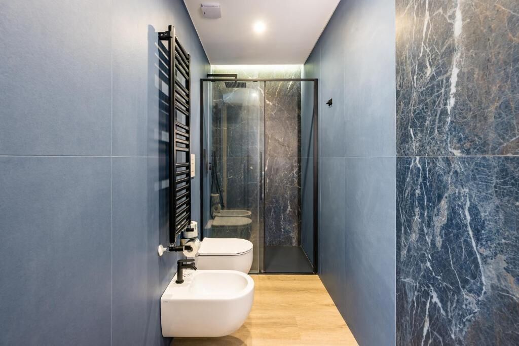 A modern bathroom with a bidet, toilet, and glass shower enclosure.