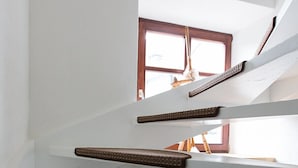 Un intérieur à plusieurs niveaux avec des murs blancs, une fenêtre en bois et un radiateur.