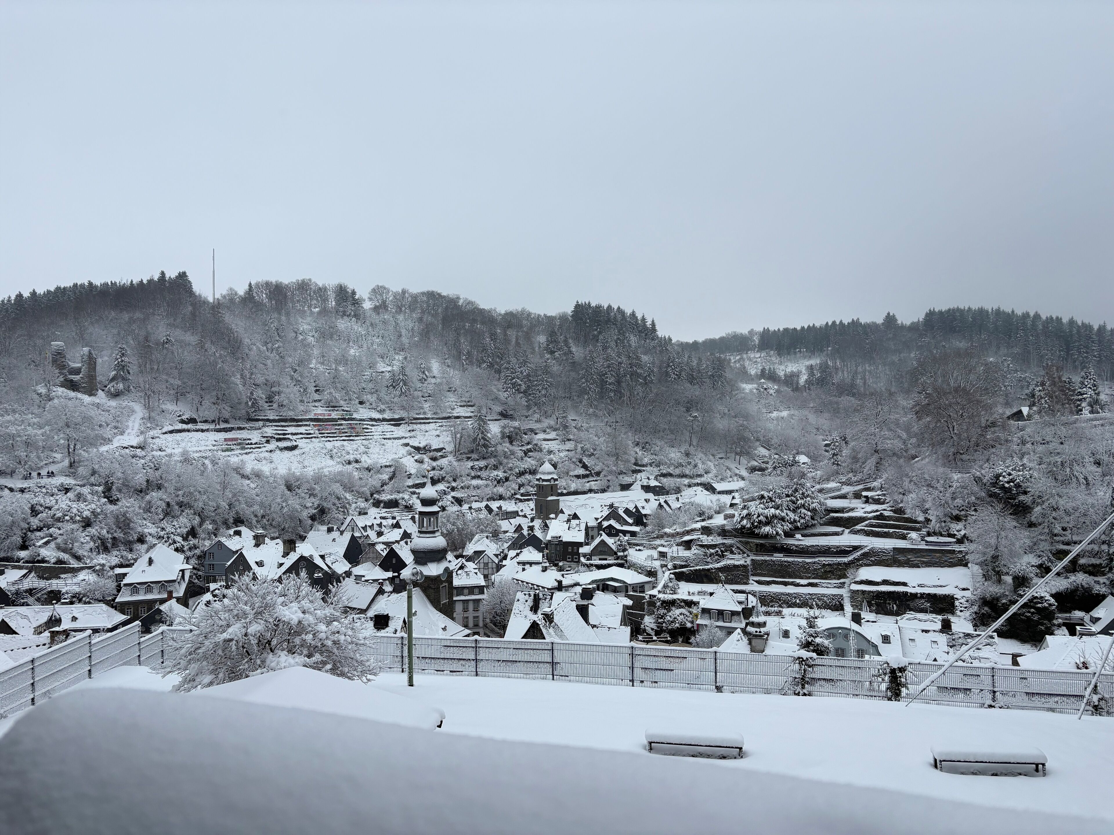 A snow-covered village with traditional houses and a hilly backdrop.
