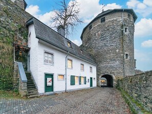 A stone tower and a white building with a staircase and green shutters. - Stone Cottage - At the Donkey Tower, below the castle (Monschau)