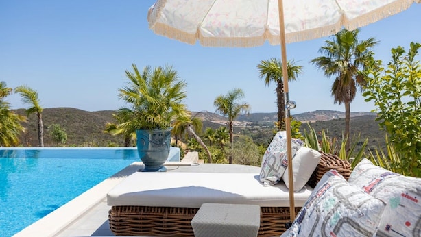 A poolside area with a wicker sofa, a large decorative bowl, and an umbrella. - Bedroom in a Villa, Budens (Vila do Bispo)