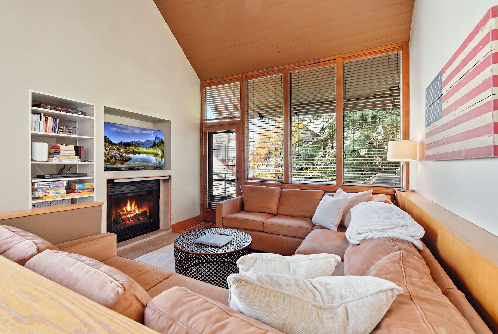 A cozy living room with a fireplace, leather sofa, and a bookshelf.