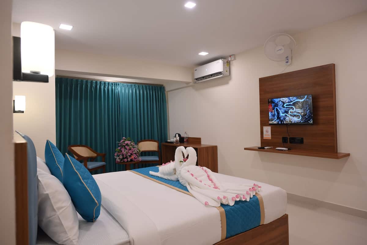 A hotel room with a bed, a TV, a desk, and a chair.