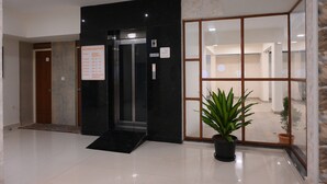 A hotel lobby with a black elevator, a building directory sign, and a potted plant. - Visthara Elite (Bengaluru)